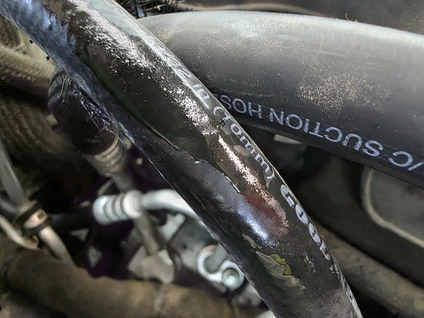 Oily, worn AC suction hose in an engine bay