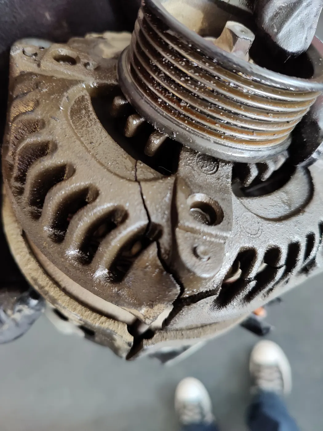 Removed alternator with a worn pulley and cracked housing
