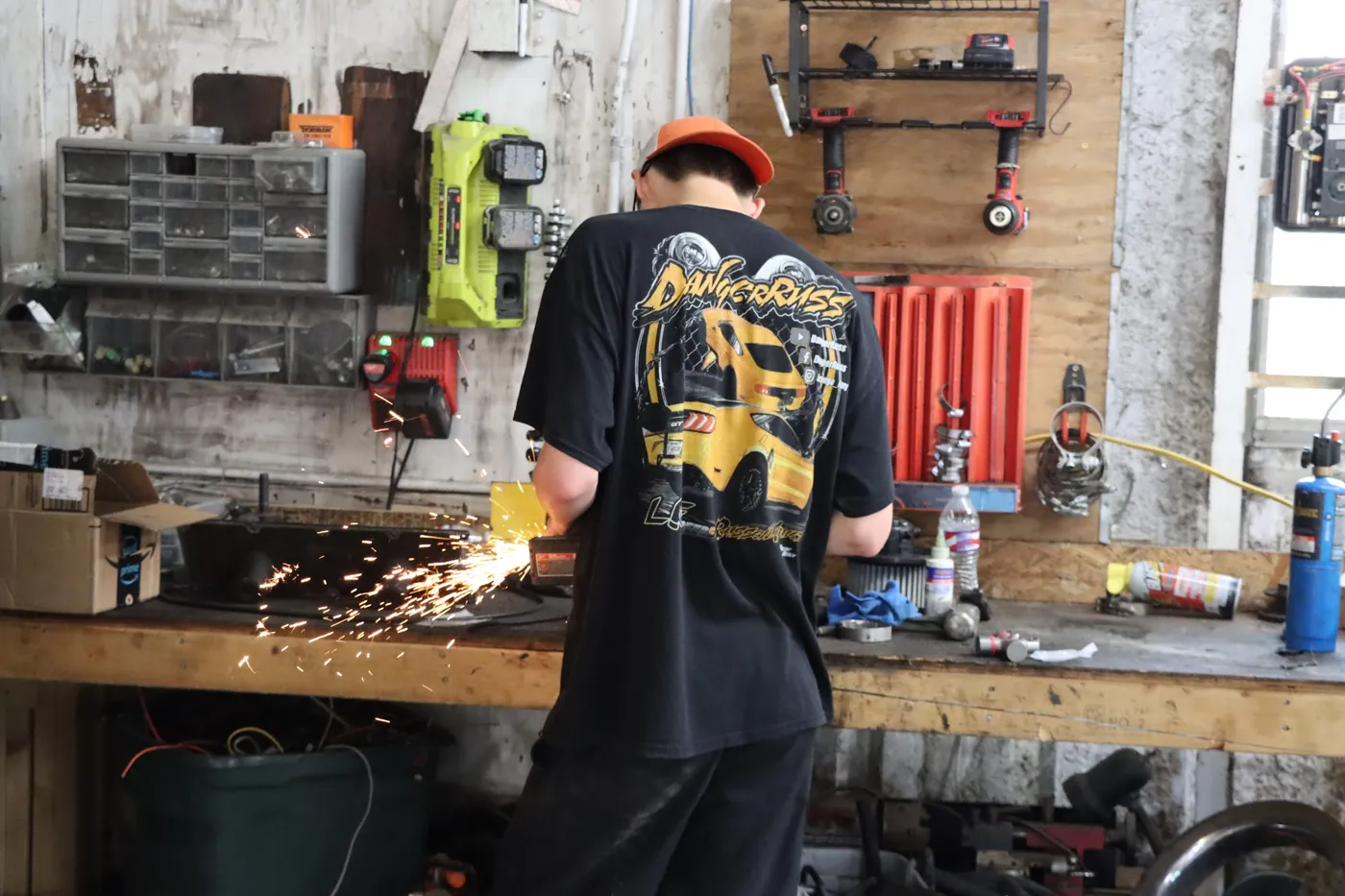 Technician cutting metal at the shop workbench, sparks flying