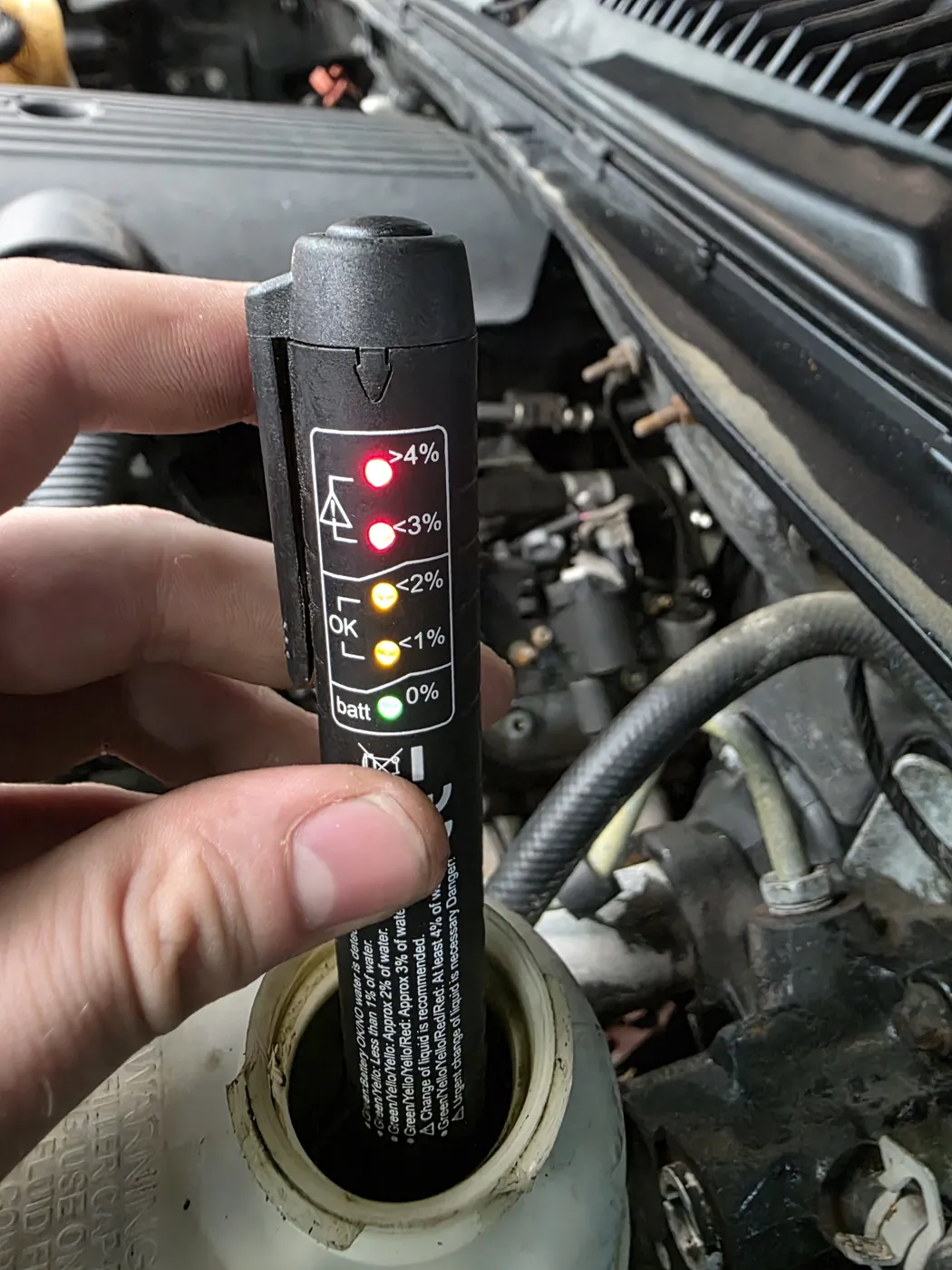 Technician testing brake fluid moisture with a tester in the reservoir
