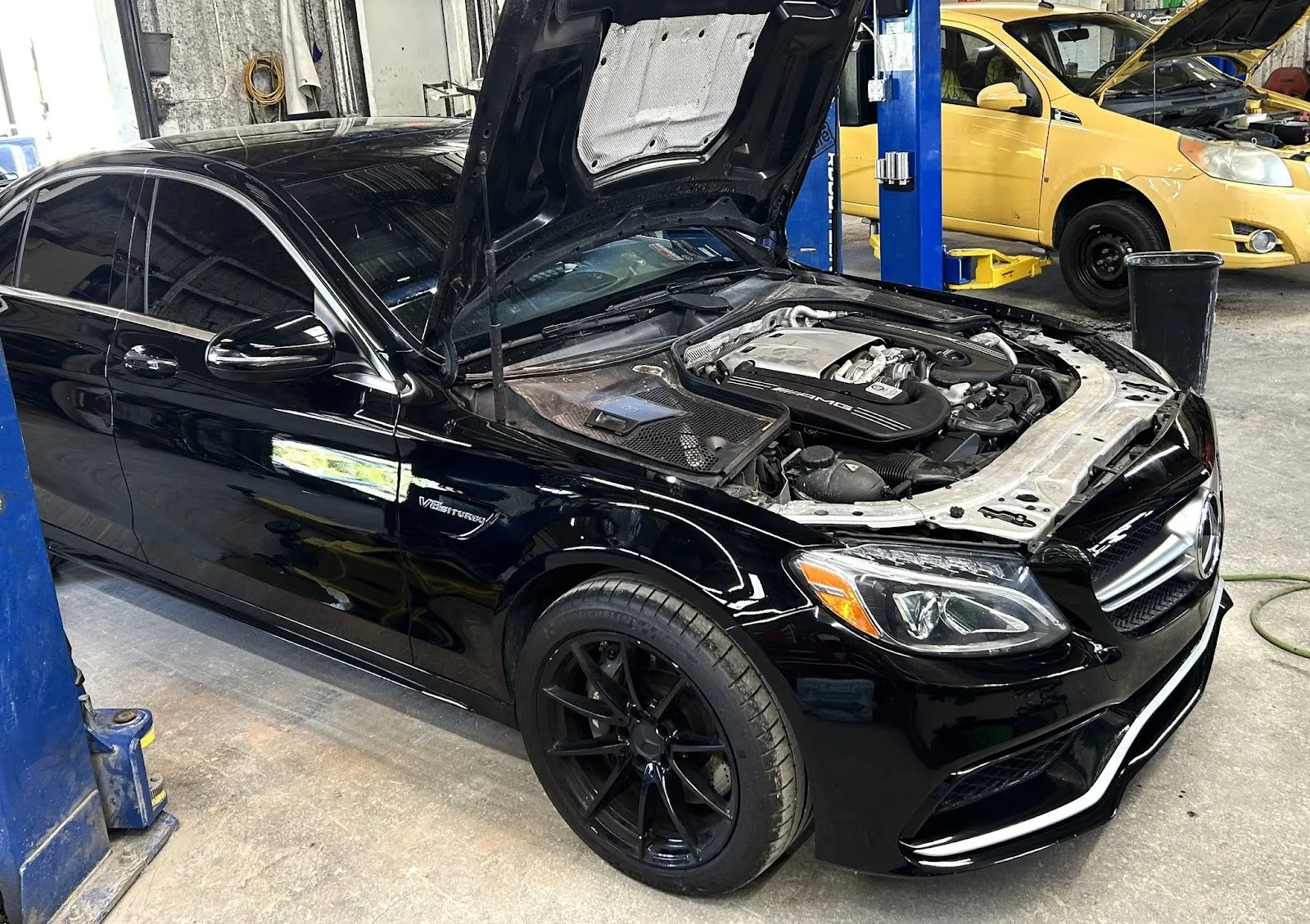 Black Mercedes-AMG C63 with the hood open on a lift