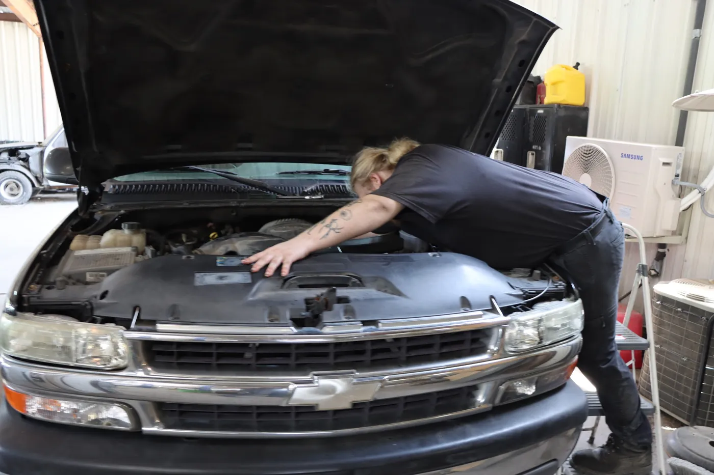 Technician leaning into the engine bay of a Chevrolet truck
