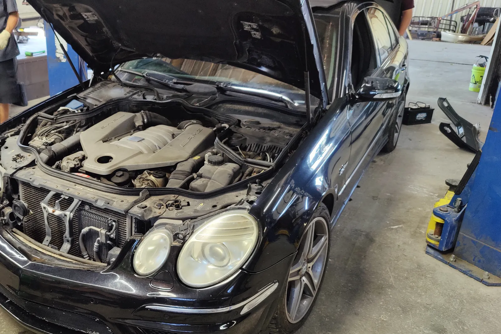Black Mercedes-Benz E63 AMG with the hood open in the service bay
