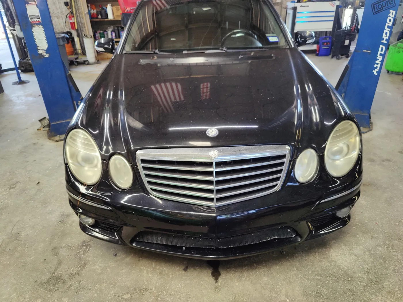 Black Mercedes-Benz E63 AMG with the hood open in the shop