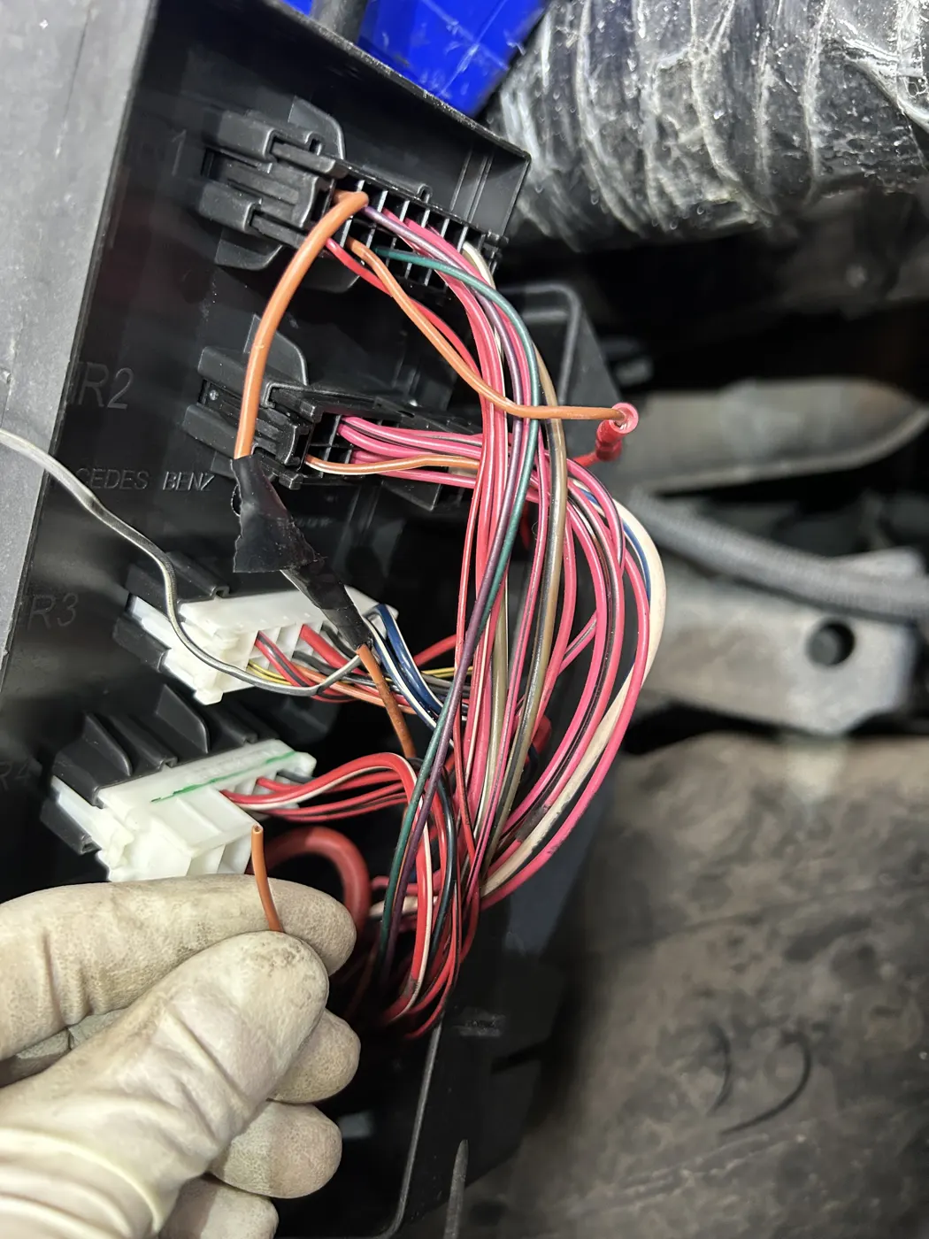 Technician tracing a wiring harness under the dash