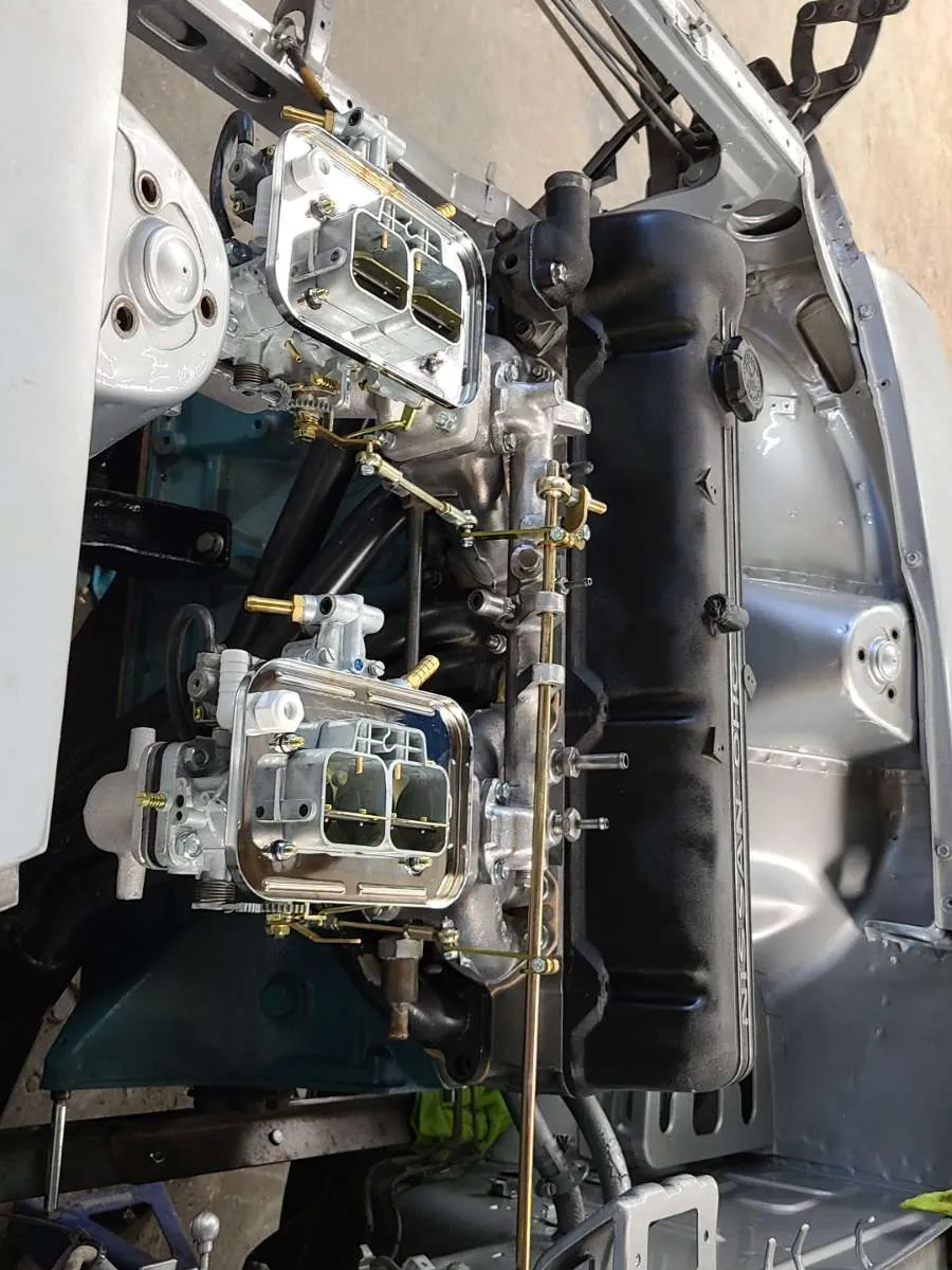 Engine with twin carburetors being assembled in the engine bay