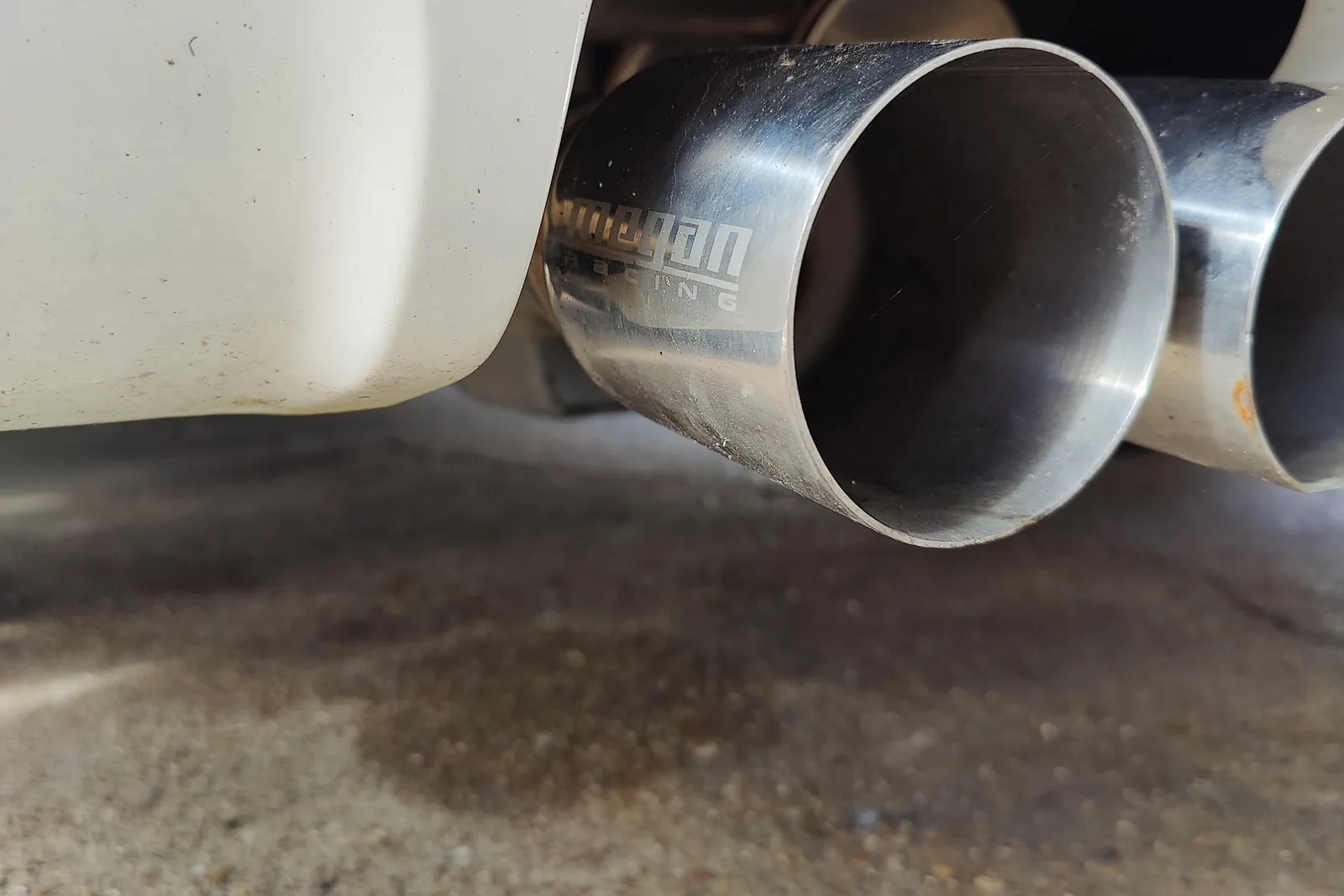 Stainless steel exhaust tips on a white car at the Figure Automotive shop