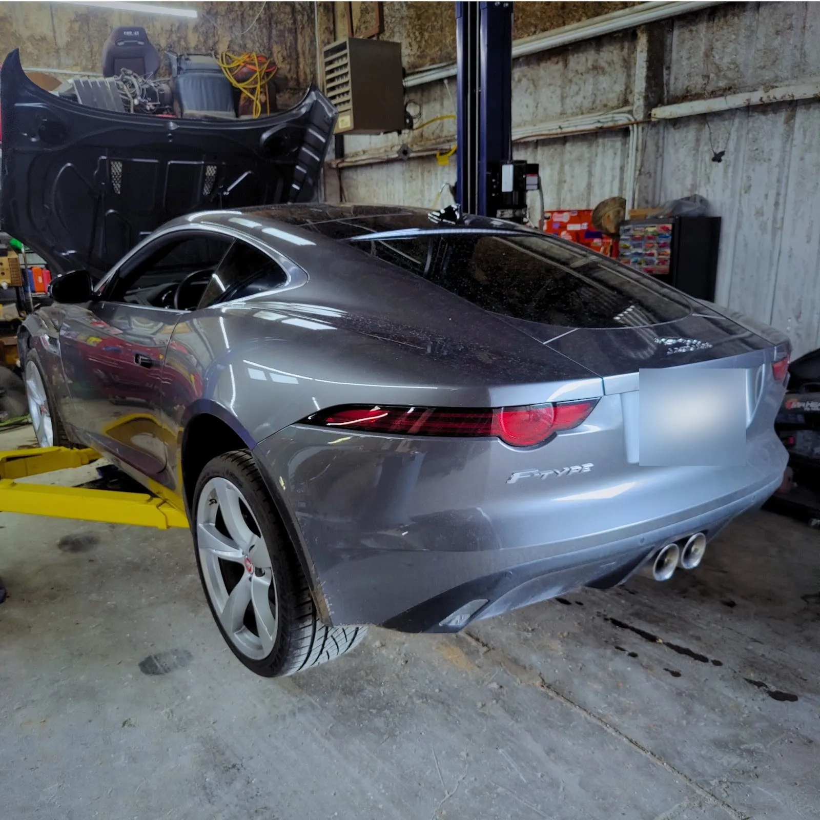 Grey Jaguar F-Type on a lift in the shop