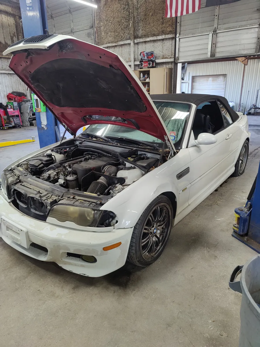 White BMW M3 convertible with the hood up in the shop, American flag on the wall
