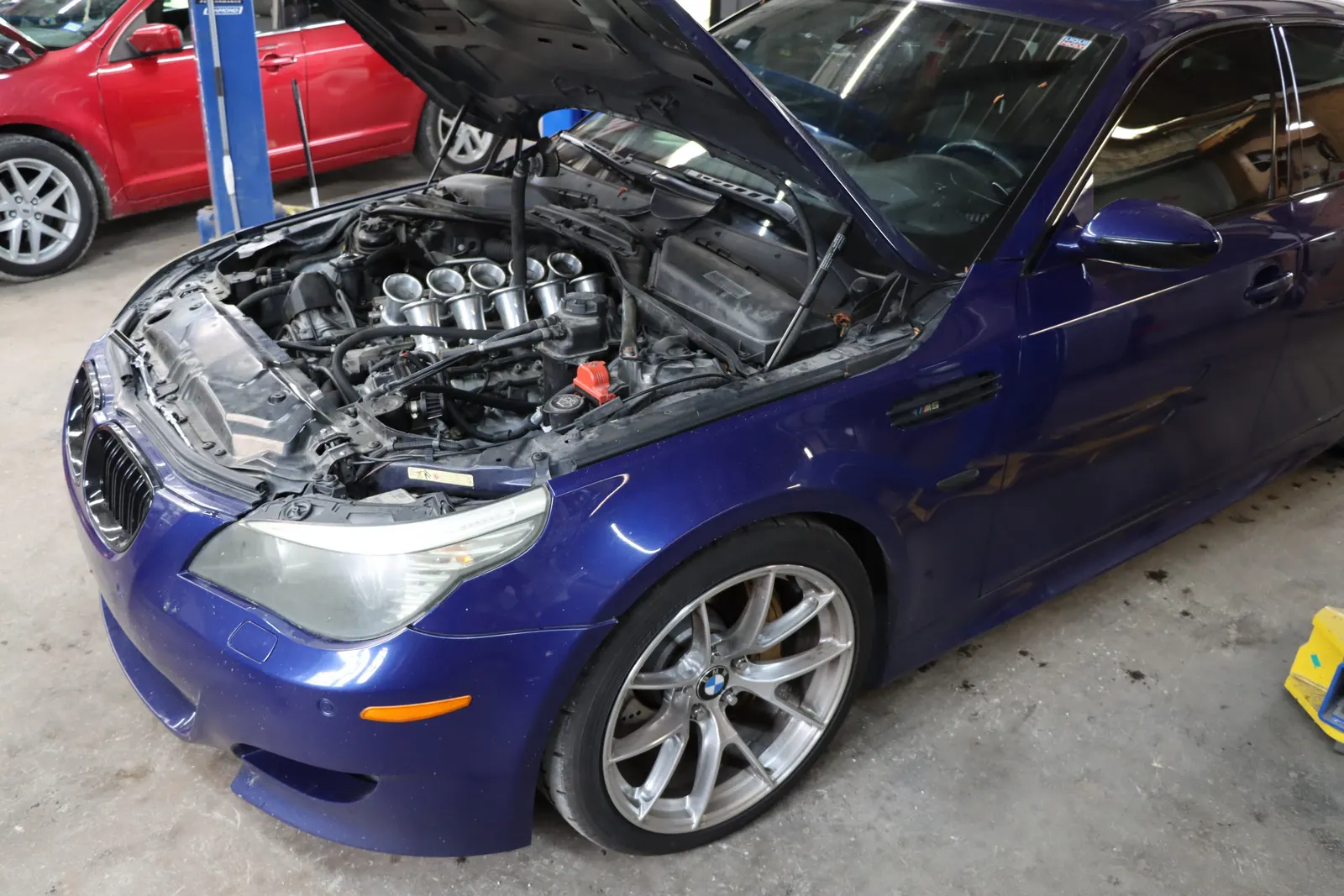 Blue BMW M5 with the hood open and its V10 intake exposed