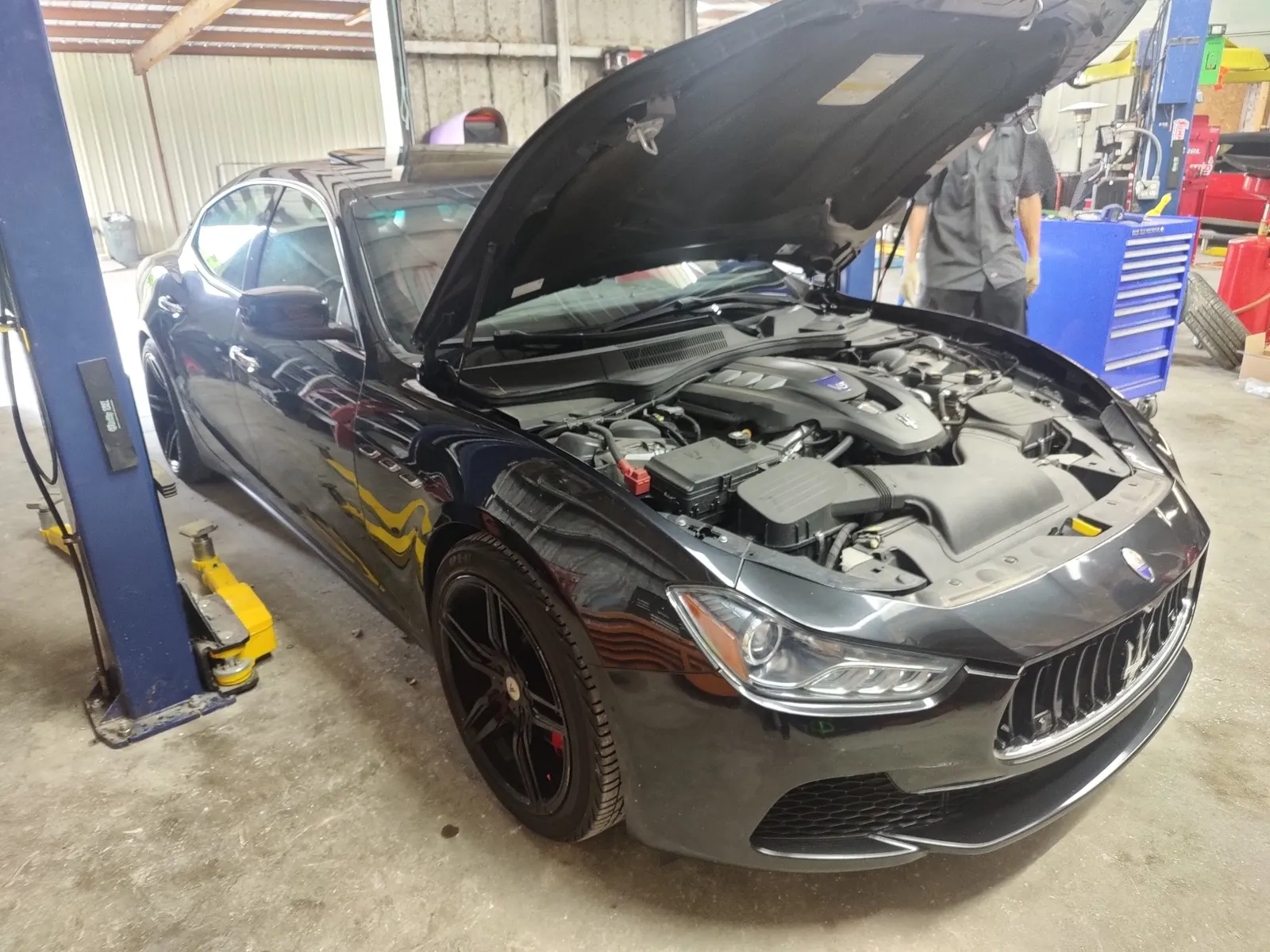 Black Maserati Ghibli with the hood open on a lift