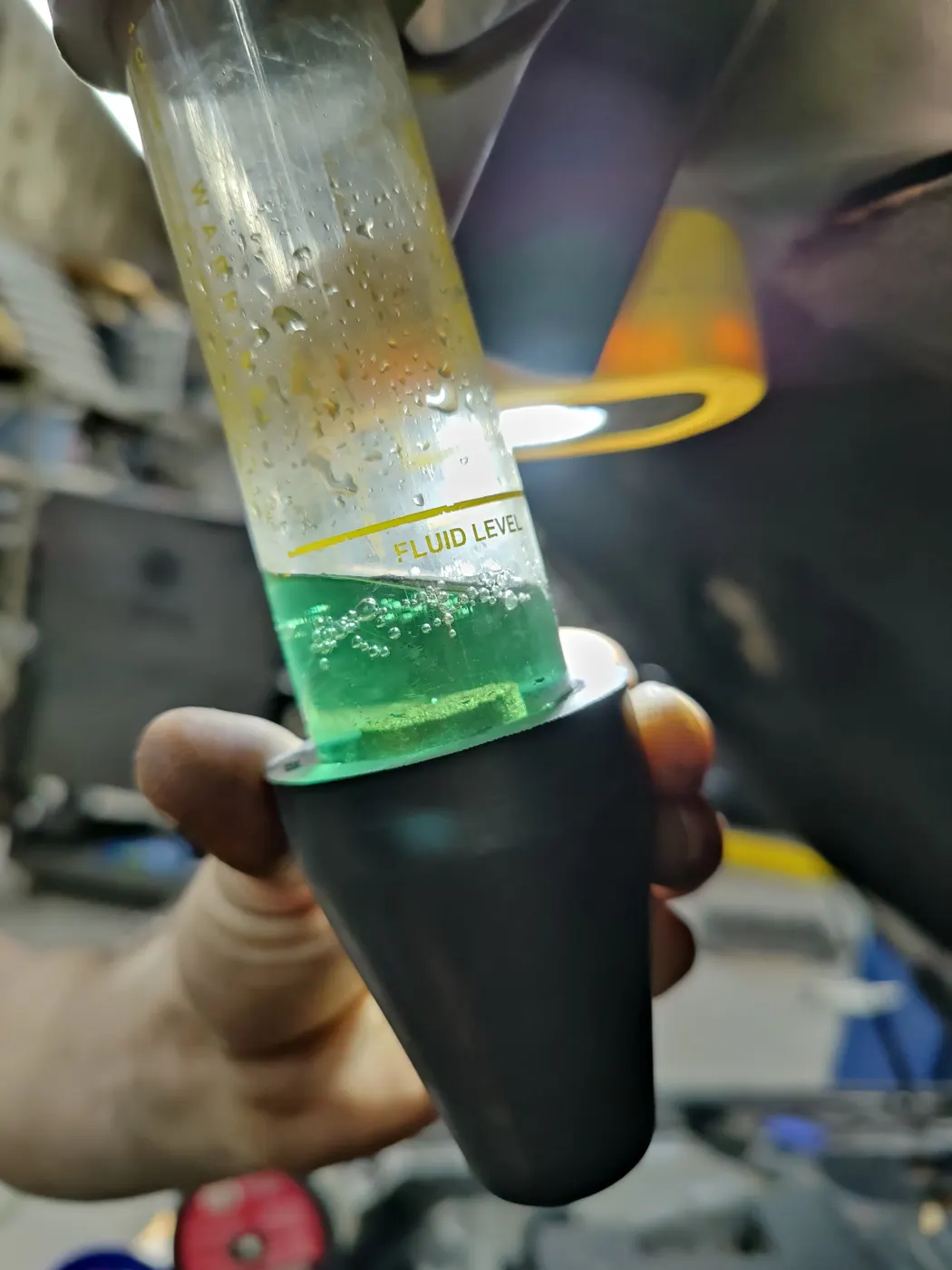 Technician checking coolant with a hydrometer tester