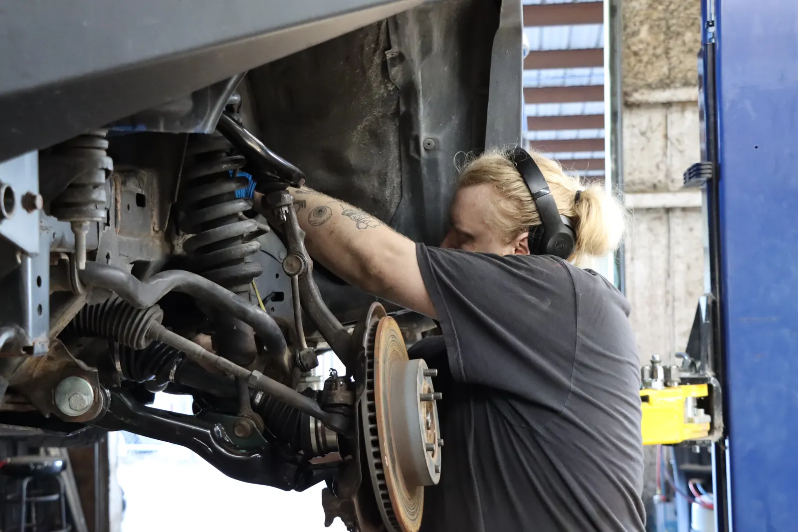 Technician working on the front suspension and brakes of a car on a lift